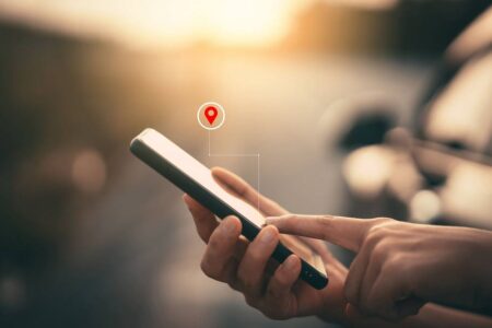 Lokalizowanie telefonu – jak to działa? Kobieta trzyma w dłoni smartfon z włączoną funkcją lokalizacji po GPS, która pokazuje jej, gdzie dokładnie się znajduje