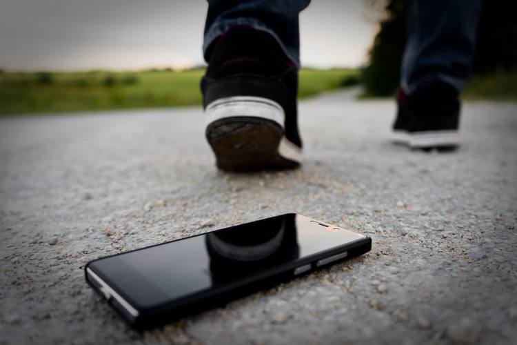 Zgubiony smartfon leży na środku ulicy, a mężczyzna od niego odchodzi, by później go znaleźć za pomocą lokalizacji telefonu