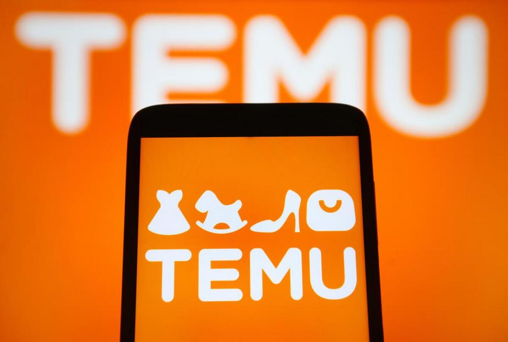 Logo Temu wyświetlane na ekranie smartfona na pomarańczowym tle